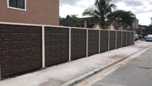 A newly installed textured concrete fence along a sidewalk by Miami Concrete Fence in Miami, FL