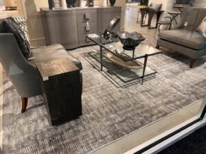 A textured grey rug displayed in a furniture showroom setting at Makymo in Commerce, CA