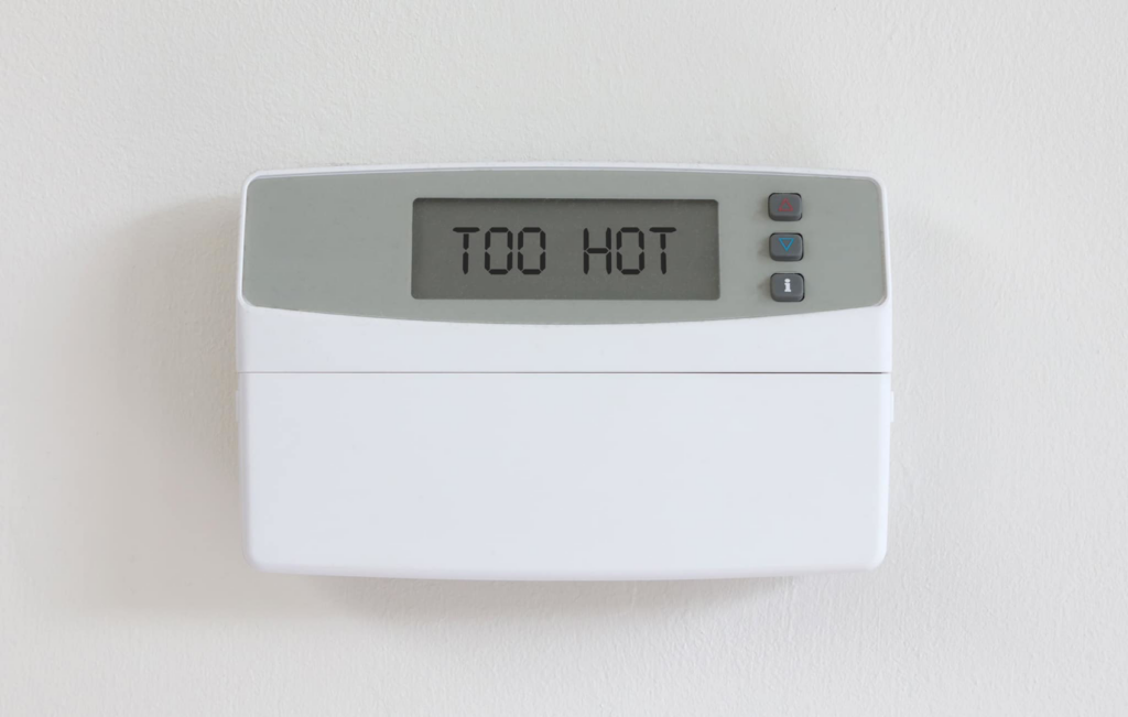A digital thermostat displaying 'TOO HOT', indicating a need for HVAC service from Spence Air Solutions in Odenville, AL.