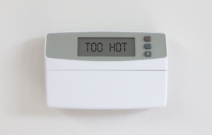 A digital thermostat displaying 'TOO HOT', indicating a need for HVAC service from Spence Air Solutions in Odenville, AL.