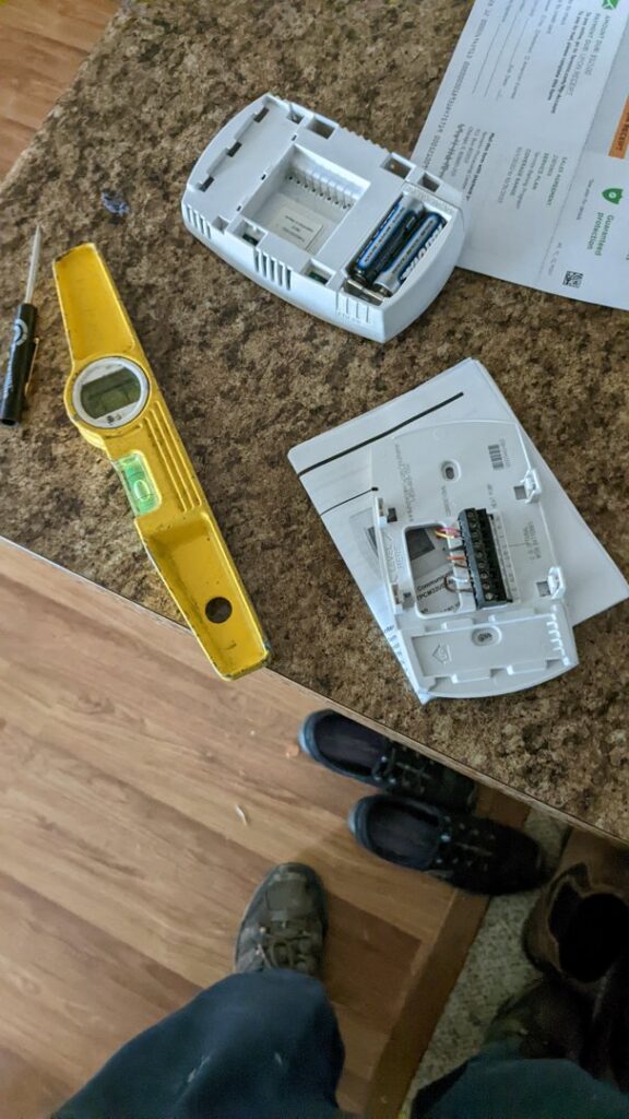 A disassembled thermostat and tools on a counter, indicating a replacement or repair by Totality Heating And Cooling in Edmond, OK.