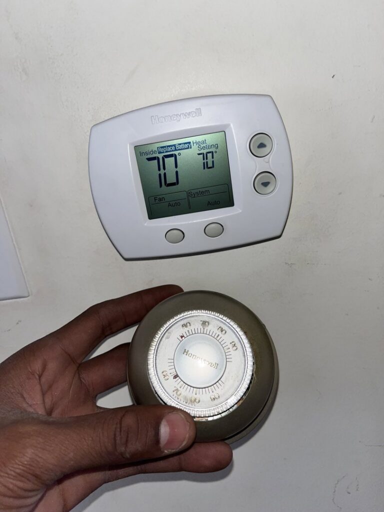 A technician holding an old thermostat next to a new digital Honeywell thermostat installed by Keith HVAC & Electrical Enterprises LLC in New Orleans, LA.