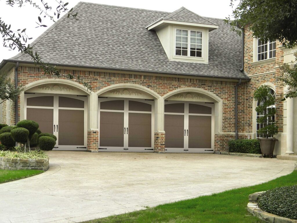 Three arched garage doors installed on a beautiful brick home by Overhead Door Company of Salem in Salem, OR.