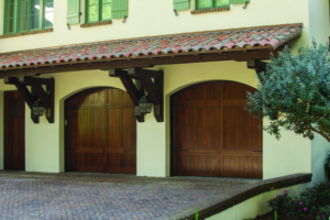Three arched dark wood garage doors on a home with a tiled roof by Overhead Door Company of the Great Plains in Lawton, OK.