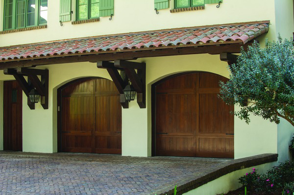 Three arched dark wood garage doors on a home with a tiled roof by Overhead Door Company of the Great Plains in Lawton, OK.