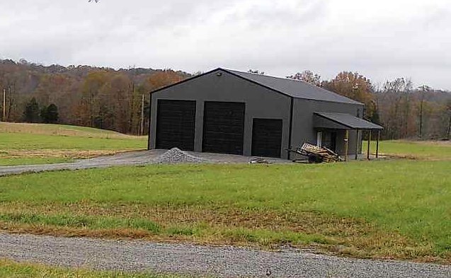 Three black garage doors installed on a grey metal building by Affordable Overhead Garage Door in Modesto, CA
