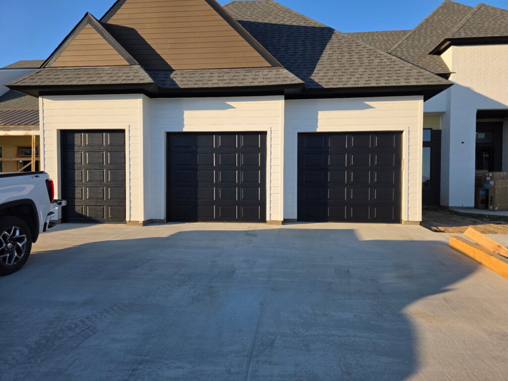 Three modern black garage doors installed on a new construction home by Legacy Garage Doors & Repairs in Church Point, LA.