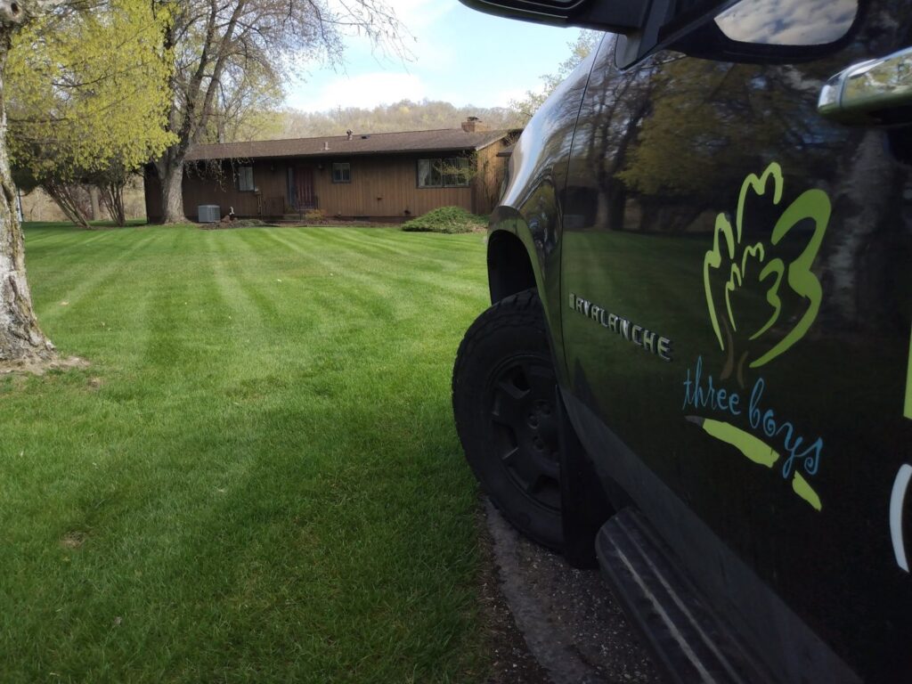 The Three Boys Lawncare branded truck parked near a perfectly mowed yard in Rochester, MN, ready for the next job.