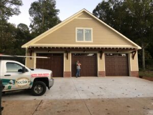 Three newly installed brown garage doors on a new construction home by Precision Door Service of Huntsville, AL.