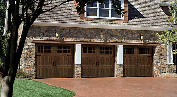 A stone house featuring three new brown garage doors with windows installed by Frankfort Overhead door Sales & Service in Frankfort, KY