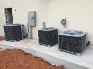 Three new Carrier HVAC condenser units professionally installed outside a building by Prudhom Mechanical LLC in Edmond, OK