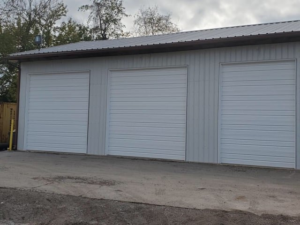 Three newly installed white commercial roll-up garage doors on a metal building by Midland Glass and Garage Doors in Frederick, MD