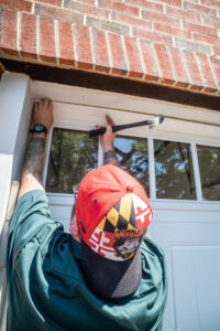 Three garage door contractors assembling a new garage door panel with windows for Annapolis Garage Doors Inc. in Annapolis, MD.
