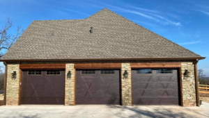 Three dark brown garage doors with windows installed on a stone facade home by Native Roots of Oklahoma in Edmond, OK