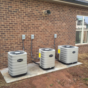 Three Frigidaire HVAC condenser units professionally installed next to a brick building by R & R H.V.A.C in Knoxville, TN.