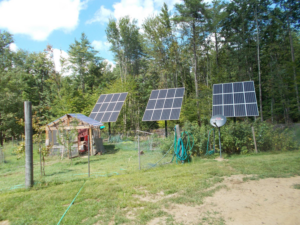 Three ground-mounted solar panels installed by Metruk's Electrical Contracting, Inc. near a shed in Underhill, VT.
