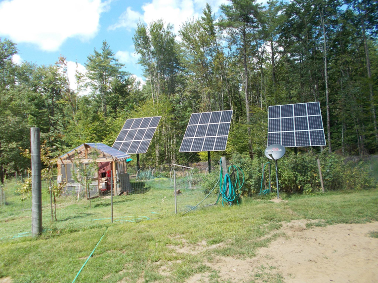 Three ground-mounted solar panels installed by Metruk's Electrical Contracting, Inc. near a shed in Underhill, VT.