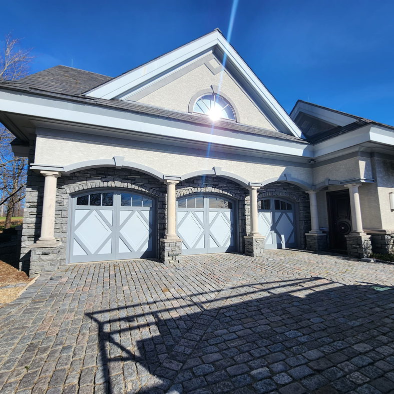 Three light grey custom garage doors with decorative panels installed by Getsinger's Overhead Doors in Spartanburg, SC.