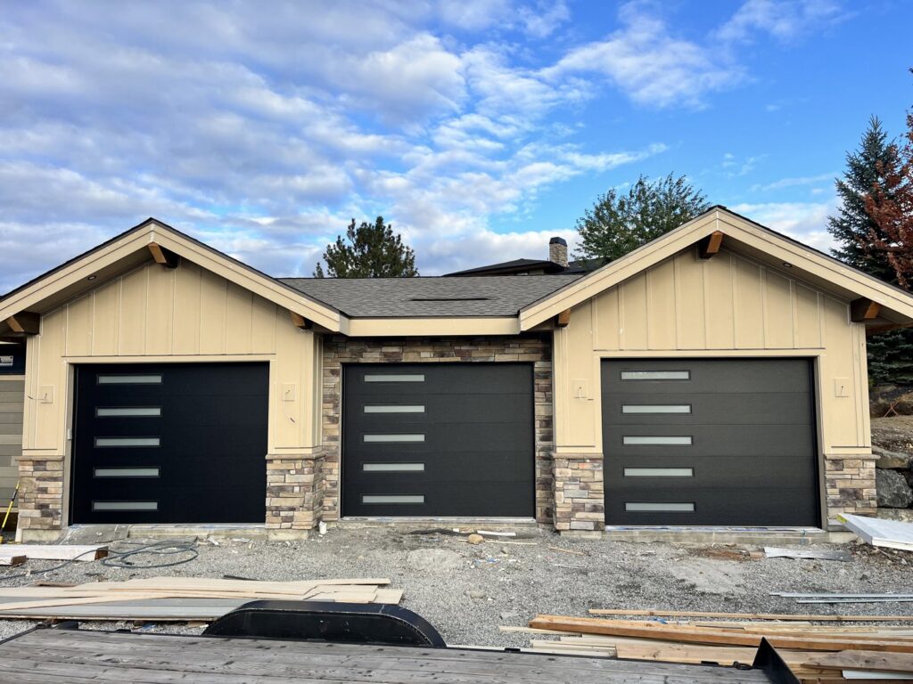 Three modern black garage doors with horizontal windows installed by Remarkable Door Company in Spokane, WA.