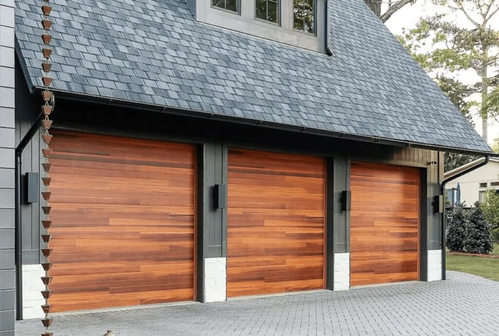 Three modern wood panel garage doors installed on a residential building, showcasing a multi-door project by Overhead Doors Unlimited, LLC in Appleton, WI.