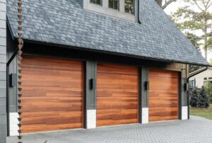 Three modern wood panel garage doors installed on a residential building, showcasing a multi-door project by Overhead Doors Unlimited, LLC in Appleton, WI.