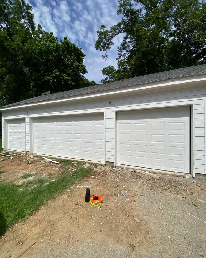 Three newly installed white garage doors on a multi-bay garage by J&C Bravo LLC in Cordova, TN.
