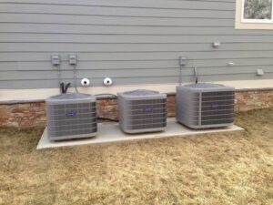 Three outdoor air conditioning units installed side-by-side on a concrete pad by 495 HVAC in Annandale, VA.