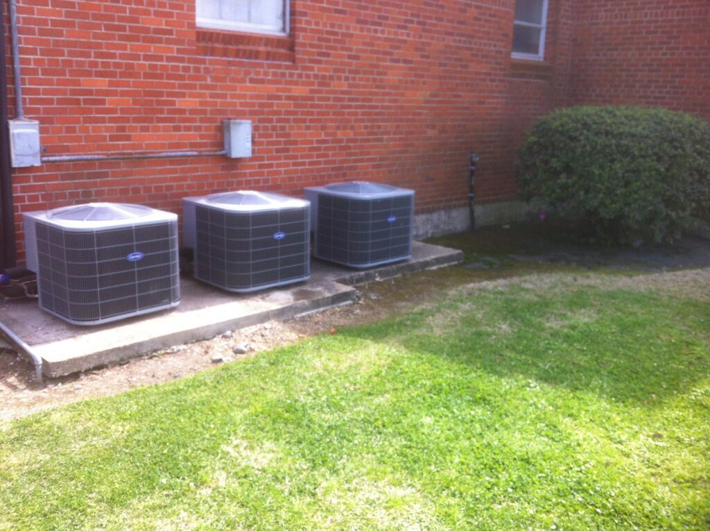 Three outdoor air conditioning units professionally installed next to a brick building by R&B Cooling&Heating in Abbeville, LA.
