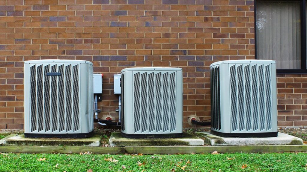 Three outdoor HVAC condenser units installed next to a brick building by A-OK Heating & Cooling in Concord, GA.