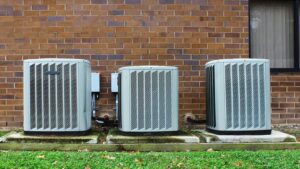 Three outdoor HVAC condenser units installed next to a brick building by A-OK Heating & Cooling in Concord, GA.