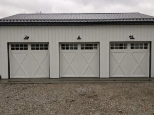 Three newly installed white carriage-style garage doors on a modern building by Summers Garage Door in Denver, CO.