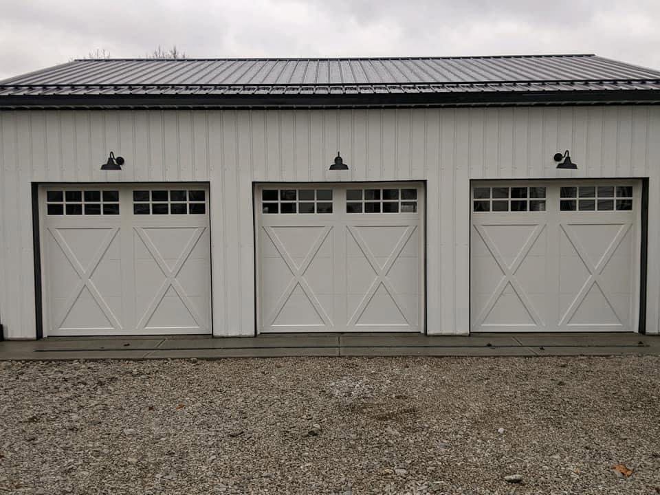 Three newly installed white carriage-style garage doors on a modern building by Summers Garage Door in Denver, CO.