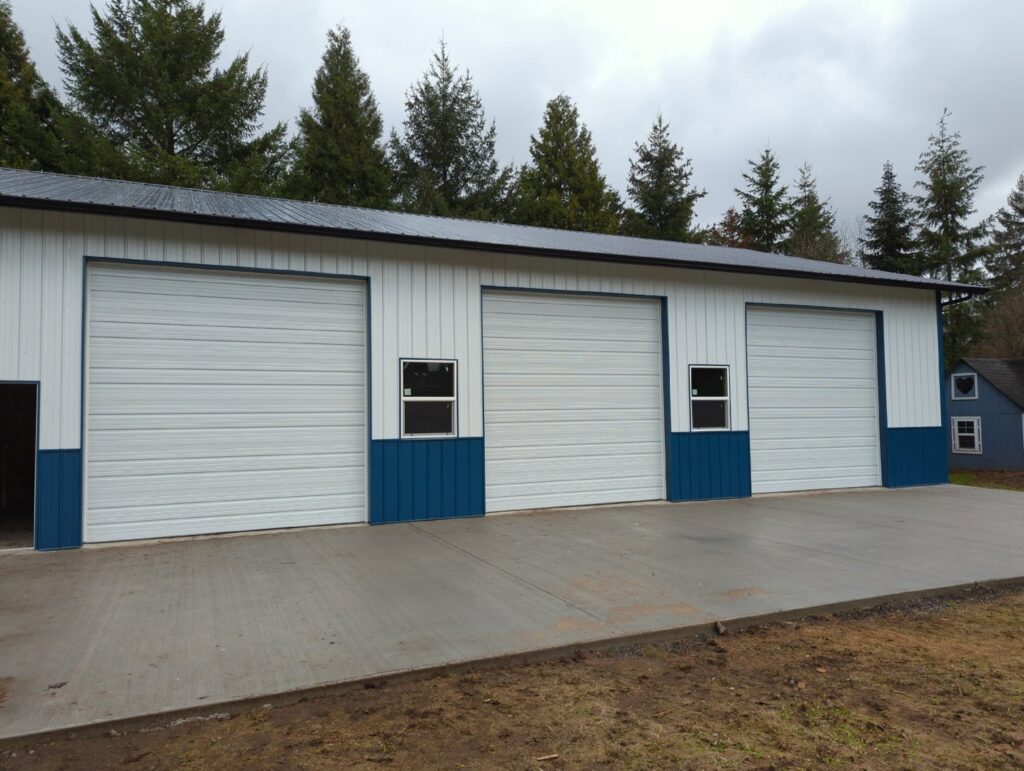 Three white commercial-style garage doors with blue trim on a large building by Babcock Garage Doors in Vancouver, WA