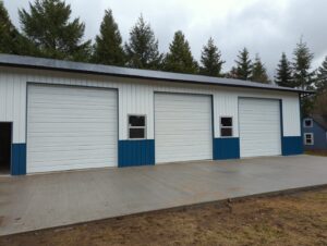 Three white commercial-style garage doors with blue trim on a large building by Babcock Garage Doors in Vancouver, WA