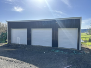 Three new white garage doors installed on a modern building by Reed's Garage Door Systems LLC in Sutherlin, OR.