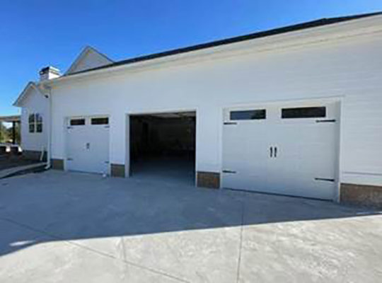 Three white garage doors, one open, on a clean white building, installed by Summers Garage Door in Denver, CO.