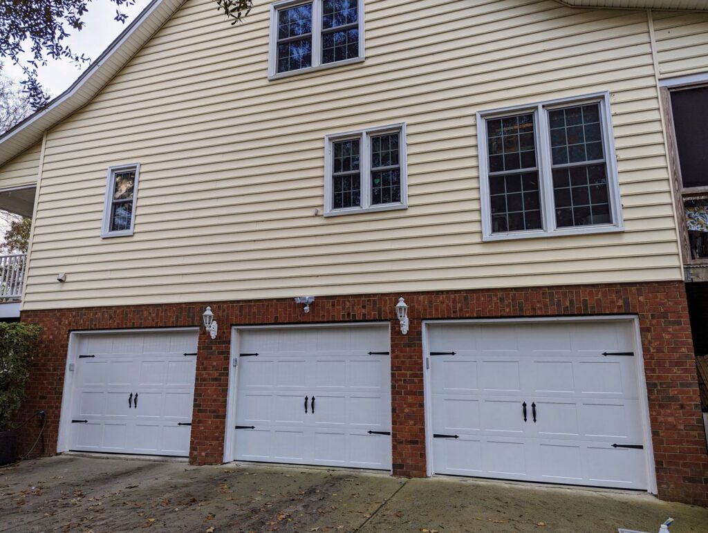 A house featuring three white garage doors installed by Precision Garage Door of Charleston in Charleston, SC.