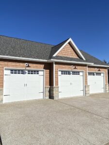 Three white residential garage doors with windows on a new construction home by 314 Overhead Doors in O'Fallon, MO.