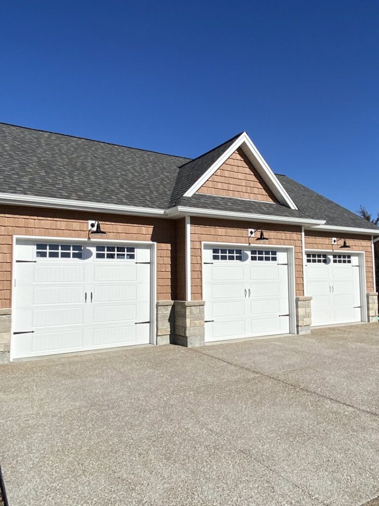 Three white residential garage doors with windows on a new construction home by 314 Overhead Doors in O'Fallon, MO.