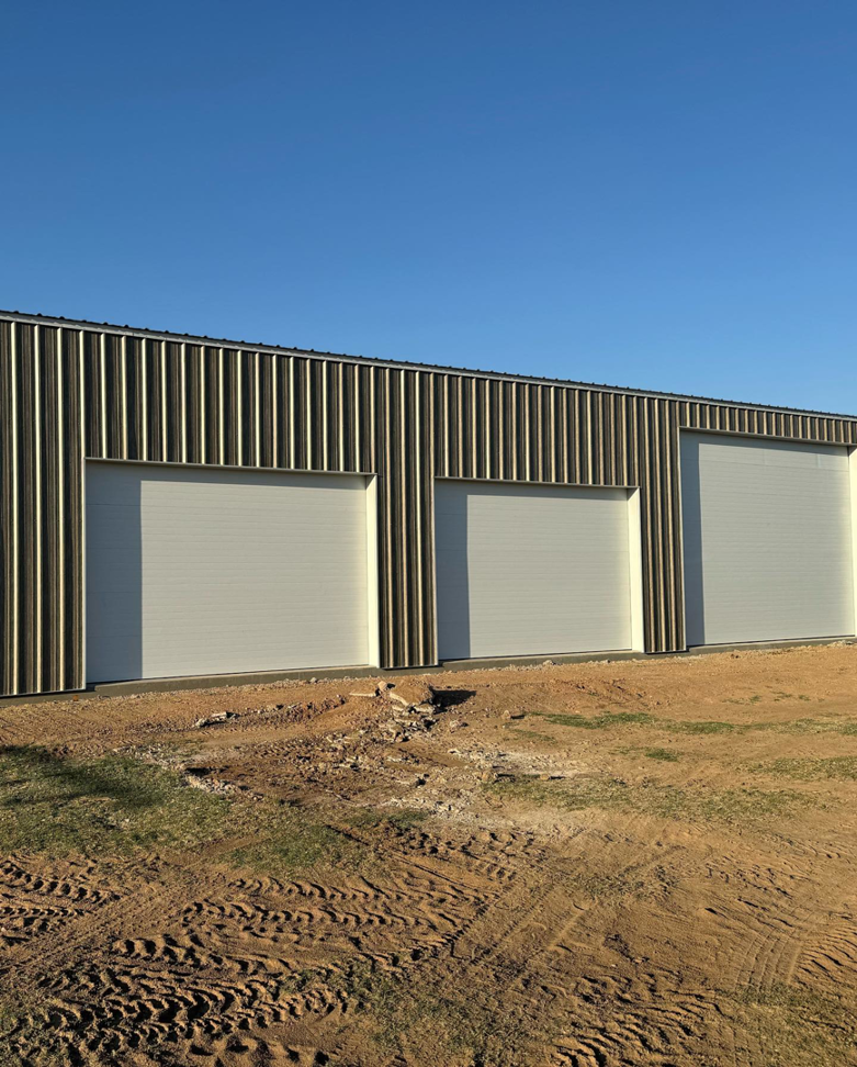 Three white sectional garage doors on a metal building installed by Mr. Garage Door in Bell Gardens, CA.