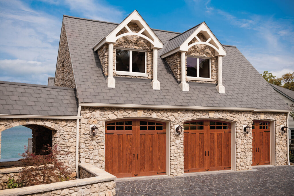 Three wood-look garage doors installed on a stone and brick house by Access Garage Doors-Chattanooga, TN