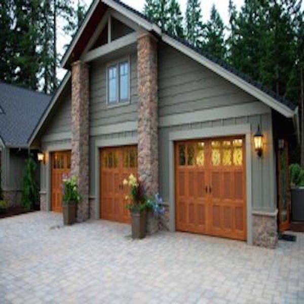 Three elegant wooden-style garage doors with windows on a large house, installed by Coast To Coast Garage Door LLC in Vancouver, WA.