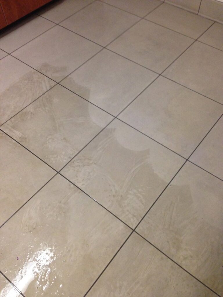 A tile floor showing the cleaning progress with a clear distinction between dirty and clean areas by Radiant Rugs Carpet Cleaning in Spokane, WA.