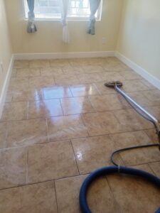 A professional tile floor cleaning service in progress with a cleaning wand and hose by Carpets Dirty in Phoenix, AZ