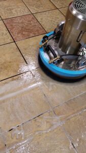 A professional scrubbing machine cleaning tile and grout, creating suds, by Carpet Care in Reisterstown, MD.