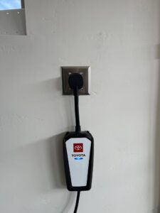 A Toyota EV charger plugged into a wall outlet, installed by LE Electric in Las Cruces, NM
