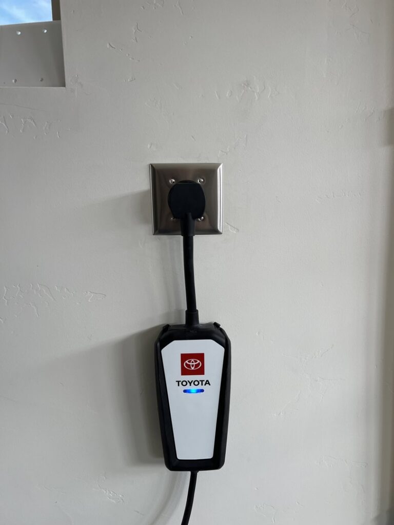 A Toyota EV charger plugged into a wall outlet, installed by LE Electric in Las Cruces, NM