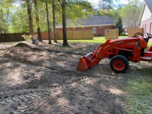 A tractor moving dirt for a landscaping or ground preparation project by L&L Lawn Care Service in Dothan, AL.