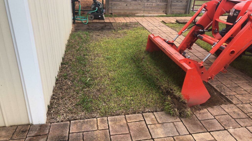 A tractor with a front loader removing sod for a landscaping project by L&L Lawn Care Service in Dothan, AL.