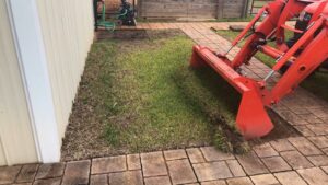 A tractor with a front loader removing sod for a landscaping project by L&L Lawn Care Service in Dothan, AL.